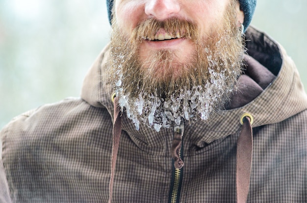 Smiling young man with beard in icicles