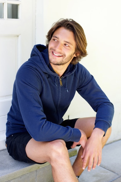 Photo smiling young man with beard sitting on patio