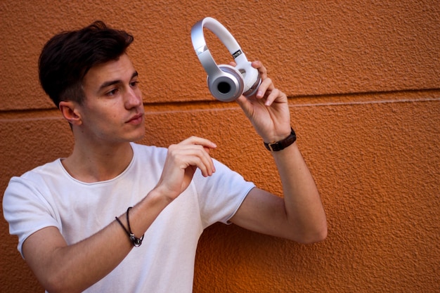 Smiling young man with headphones listening to music on the street