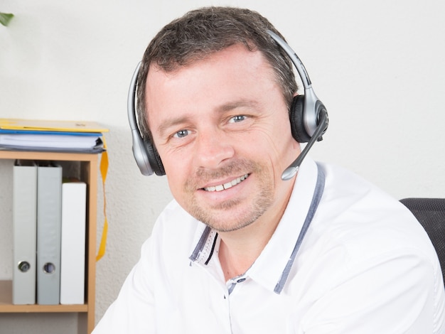 Smiling young man with headset working in call center