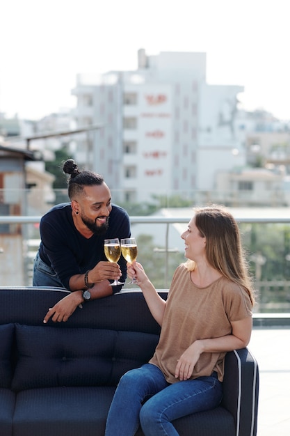 Smiling young man and woman drinking champagne and flirting at rooftp party