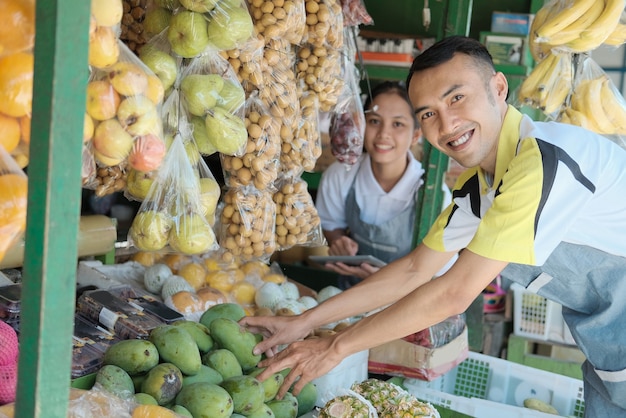 과일 가게의 구색을 표시 웃는 젊은 남자와 여자 판매자