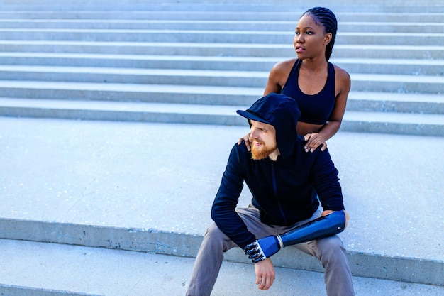 Smiling young mixed race couple in sportswear warming up outdoors sity background early morning