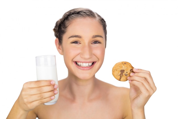 Smiling young model holding cookie and milk