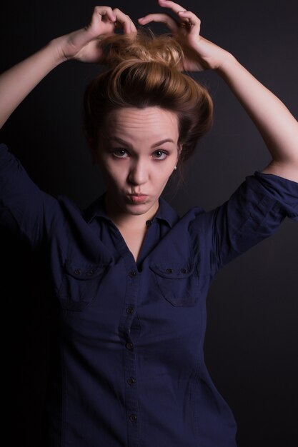 Smiling young model in trendy clothes,  posing with grimace on a dark studio background