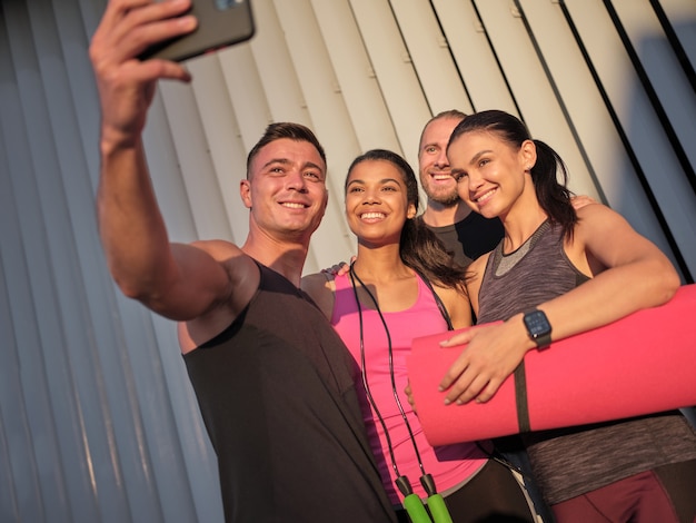 Foto sorridenti giovani sportivi multirazziali che prendono selfie