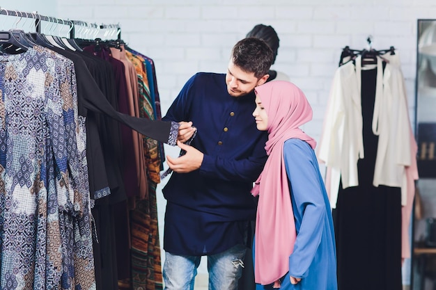 Smiling young muslim couple shopping and looking at carpets in a textile store