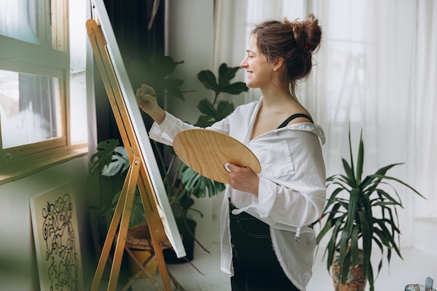 Foto sorridente giovane pittore che disegna su tela in studio