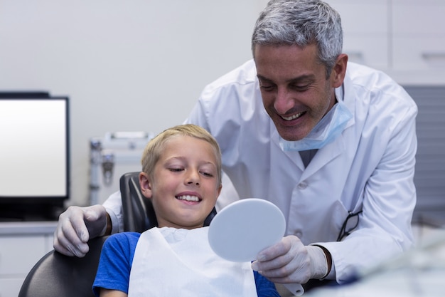 Smiling young patient looking in the mirror in dental clinic