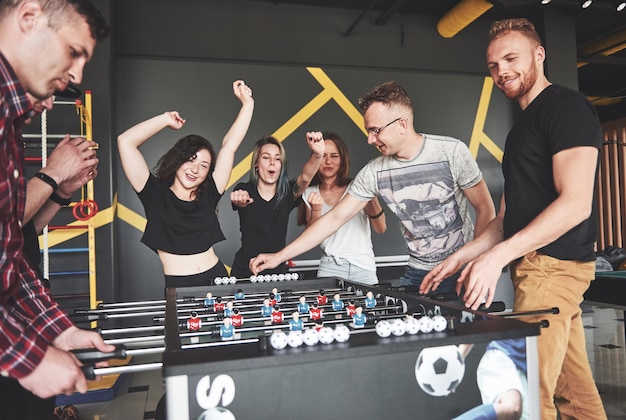 Giovani sorridenti che giocano a calcio balilla mentre sono in vacanza.