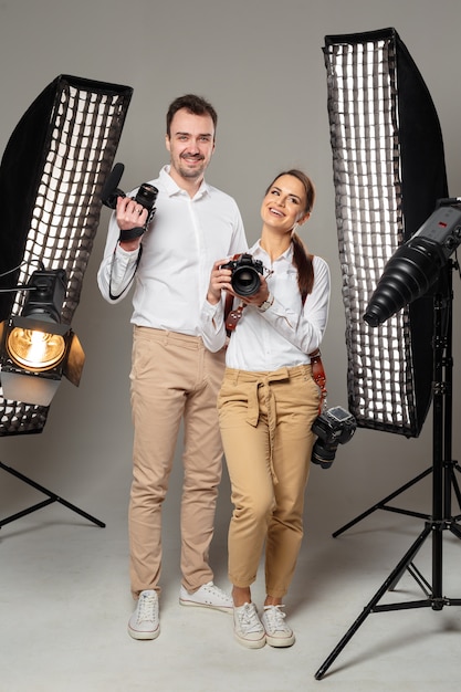 Smiling young professional photographers posing in the studio