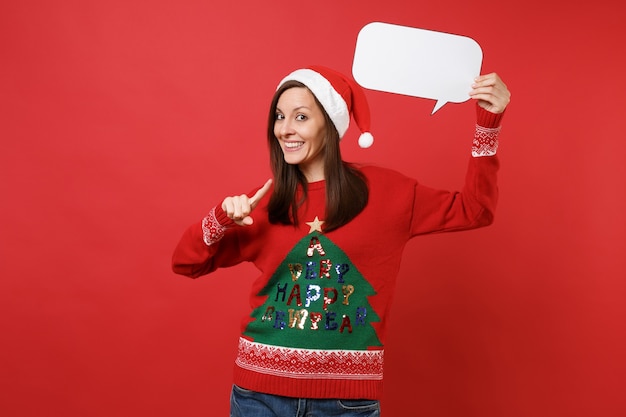 Smiling young Santa girl pointing index finger on empty blank Say cloud speech bubble in hand isolated on red background. Happy New Year 2019 celebration holiday party concept. Mock up copy space.