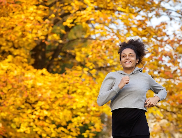 Giovane donna sorridente di sport che corre all'aperto