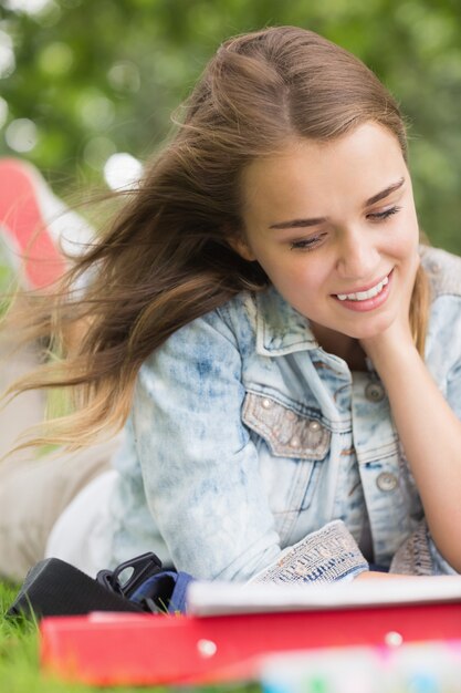 Smiling young student studying on grass