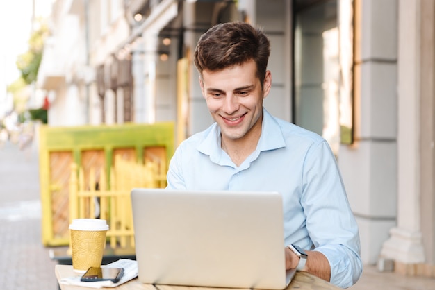 Smiling young stylish man in shirt talking on mobile phone