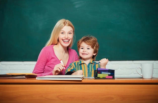 Smiling young teacher and little student school boy in a classroom