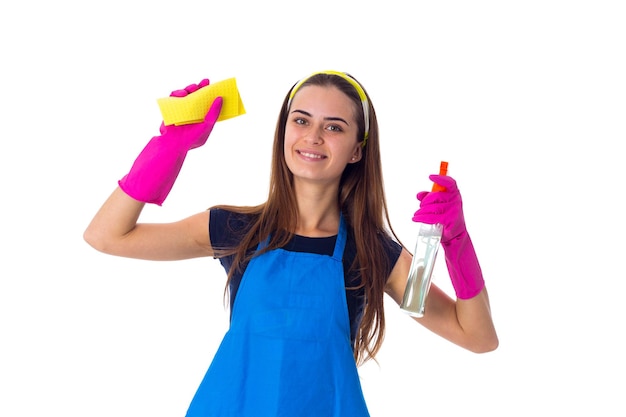 Smiling young woman in blue Tshirt and apron with pink gloves holding cleaning things in washbowl