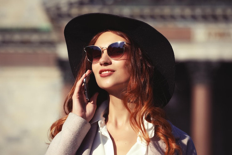 Photo smiling young woman calling and talking on smartphone in the autumn city