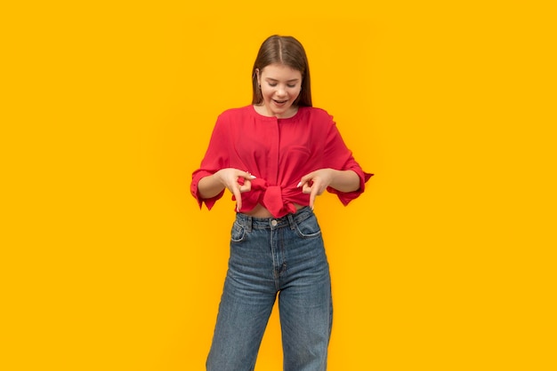 Smiling young woman in casual clothes and looking at the camera pointing with two hands to the down Copy space