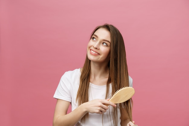 Photo smiling young woman combing hair and looking away