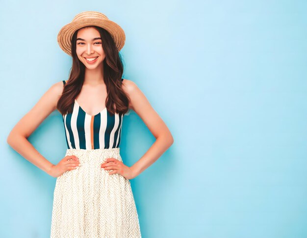 Smiling young woman dressed in fashion with hat isolated on light blue background