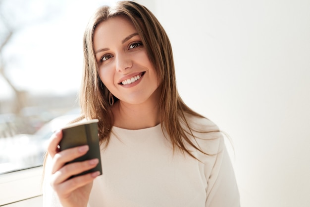 Photo smiling young woman drinking coffee from paper cup