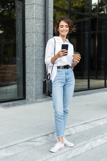 Smiling young woman in earphones standing outdoors