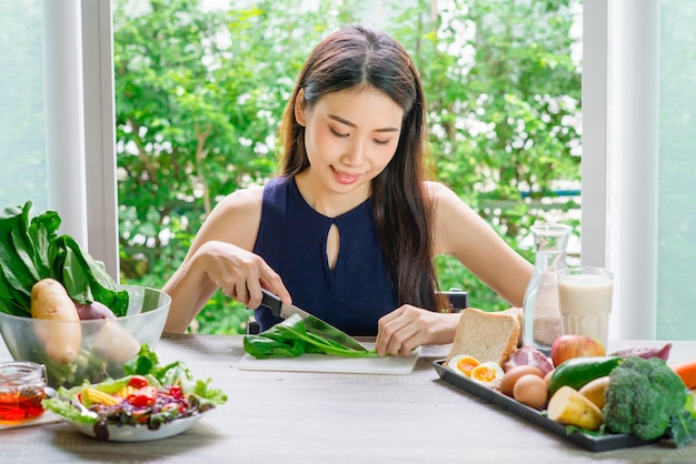 写真 テーブルで食べ物を食べている笑顔の若い女性