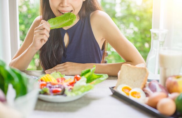 Photo smiling young woman eating food on table