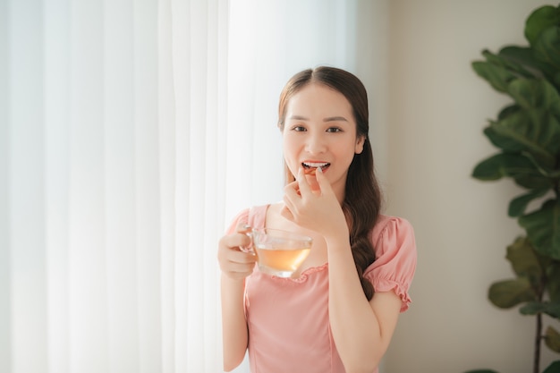 Smiling young woman eating the pill