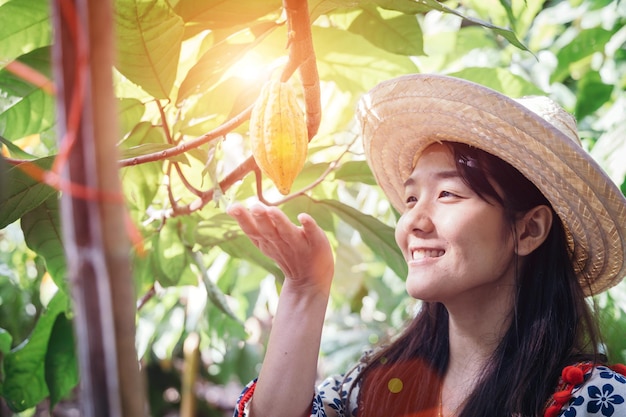 Smiling young woman in hat touching fruit