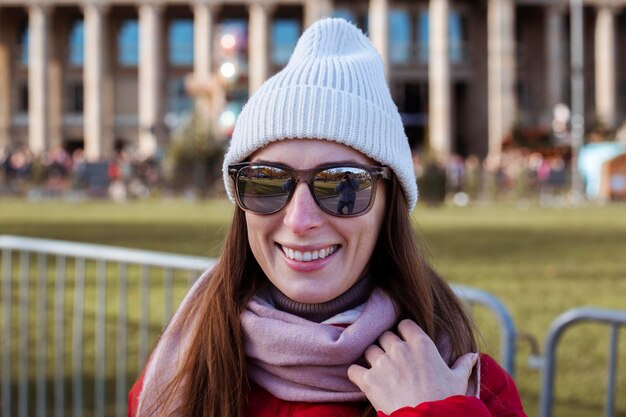 Smiling young woman in a hat with glasses on the street