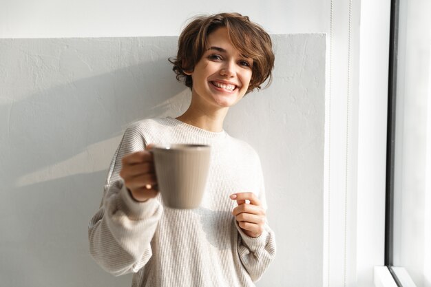 朝のキッチンでお茶を飲む若い女性の笑顔