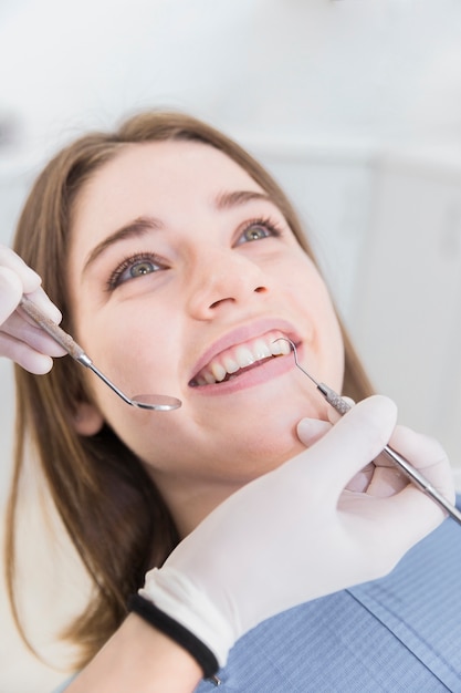 Photo smiling young woman having teeth examined at dentists