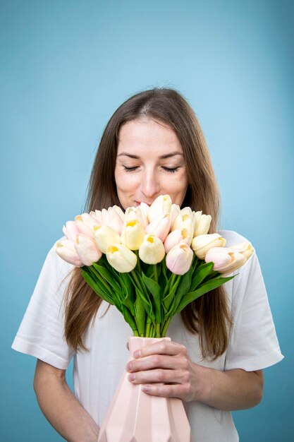 Foto sorridente giovane donna che tiene mazzo di tulipani su sfondo blu