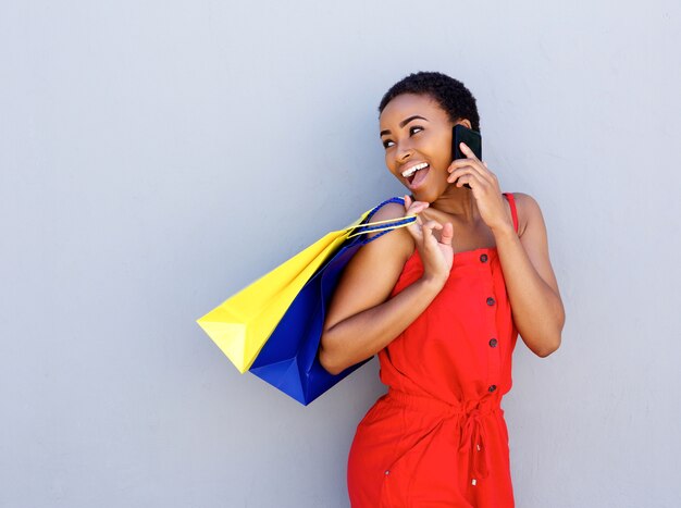 Smiling young woman holding shopping bags talking on cell phone