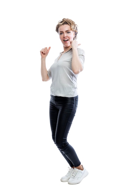 Smiling young woman is standing Beautiful blonde in black leggings a gray tshirt and white sneakers Positivity and happiness Full height Isolated on white background Vertical