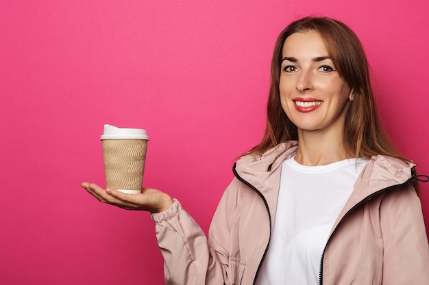 Photo smiling young woman in jacket holding paper roll on palm