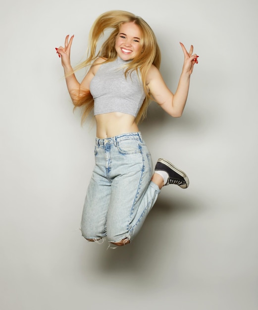 Smiling young woman jumping in air over gray background