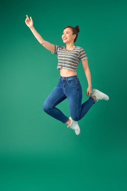 smiling young woman jumping in air over green.