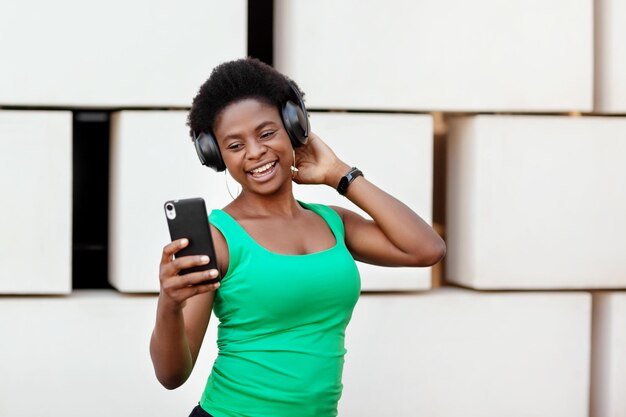 壁の向こうに立って音楽を聴いている笑顔の若い女性