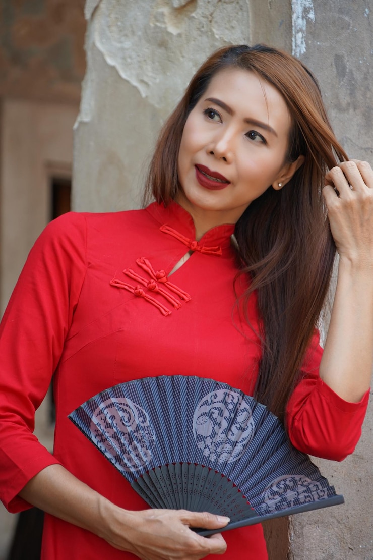 Photo smiling young woman looking away while holding hand fan