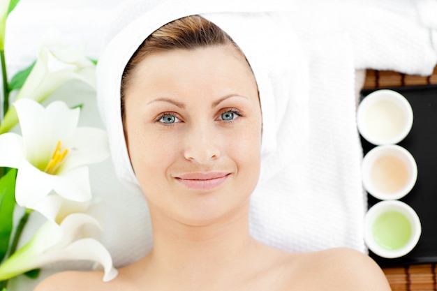 Photo smiling young woman lying on a massage table looking at the camera