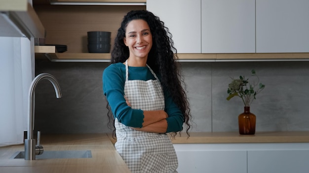 Smiling young woman maid housewife mistress baker housekeeper with long curly hair wearing checkered