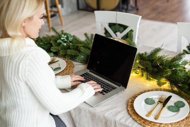 Giovane donna sorridente che fa acquisti di natale su internet.