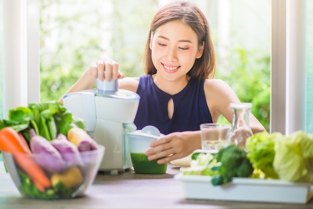 写真 家でスムージーを作っている笑顔の若い女性