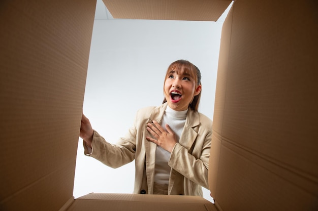 Smiling young woman opening a carton box relocation and unpacking concept