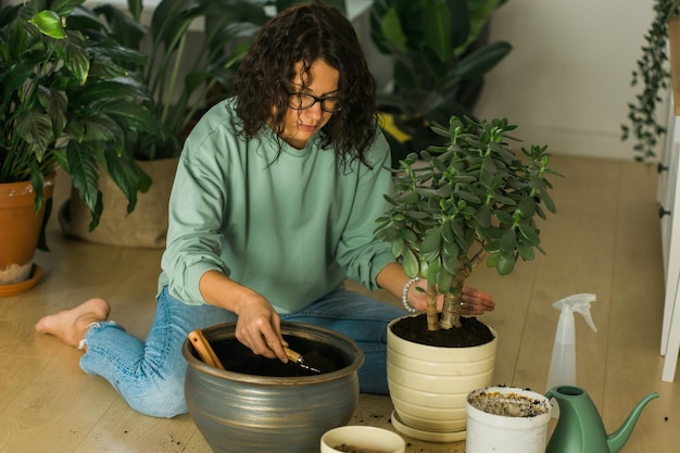 Smiling young woman and pot with plant happy work in indoor garden or cozy home office with differen