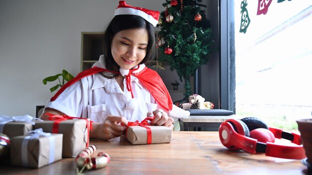Sorridente giovane donna che si prepara per il natale e avvolge i regali a casa.
