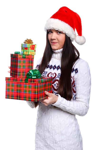 Smiling young woman in red christmass hat at white background with gifts